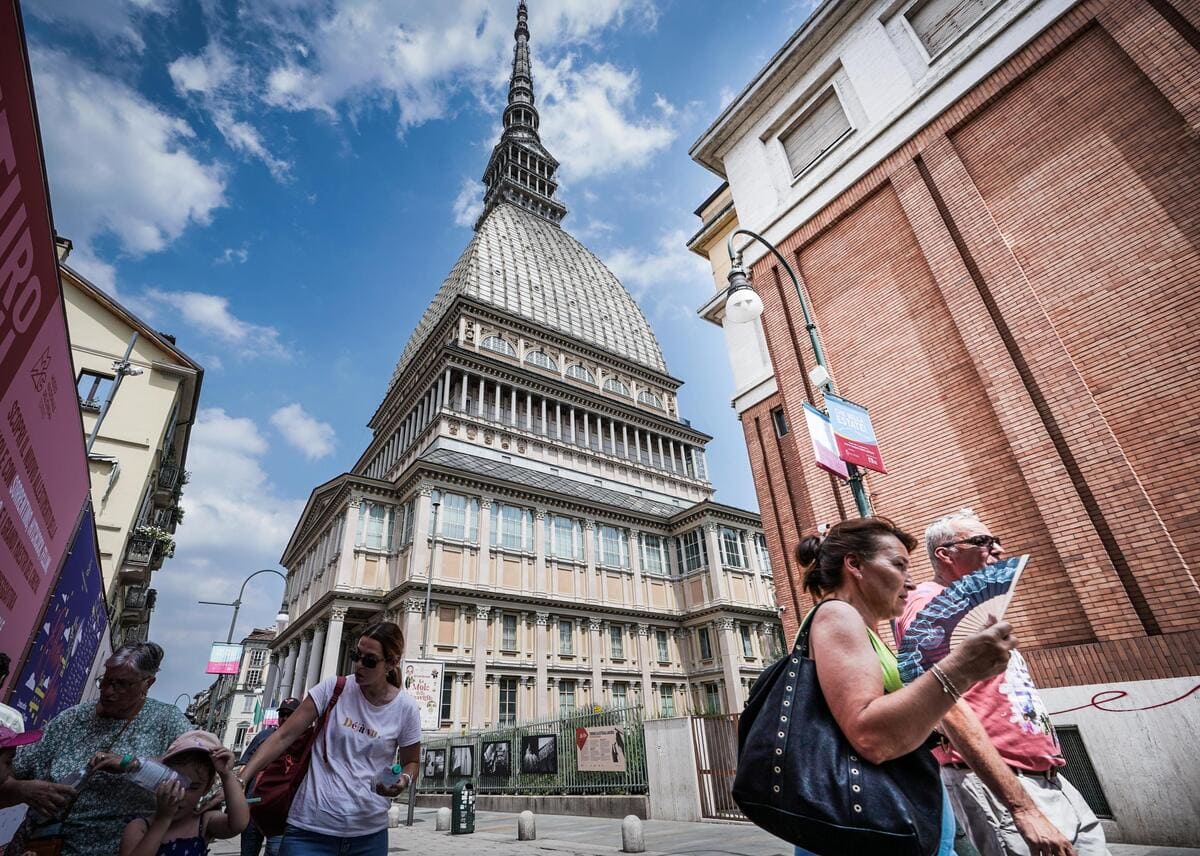 Turisti sotto la Mole Antonelliana con un ventaglio per cercare refrigerio dal caldo, Torino, 19 luglio 2023 (Ansa)