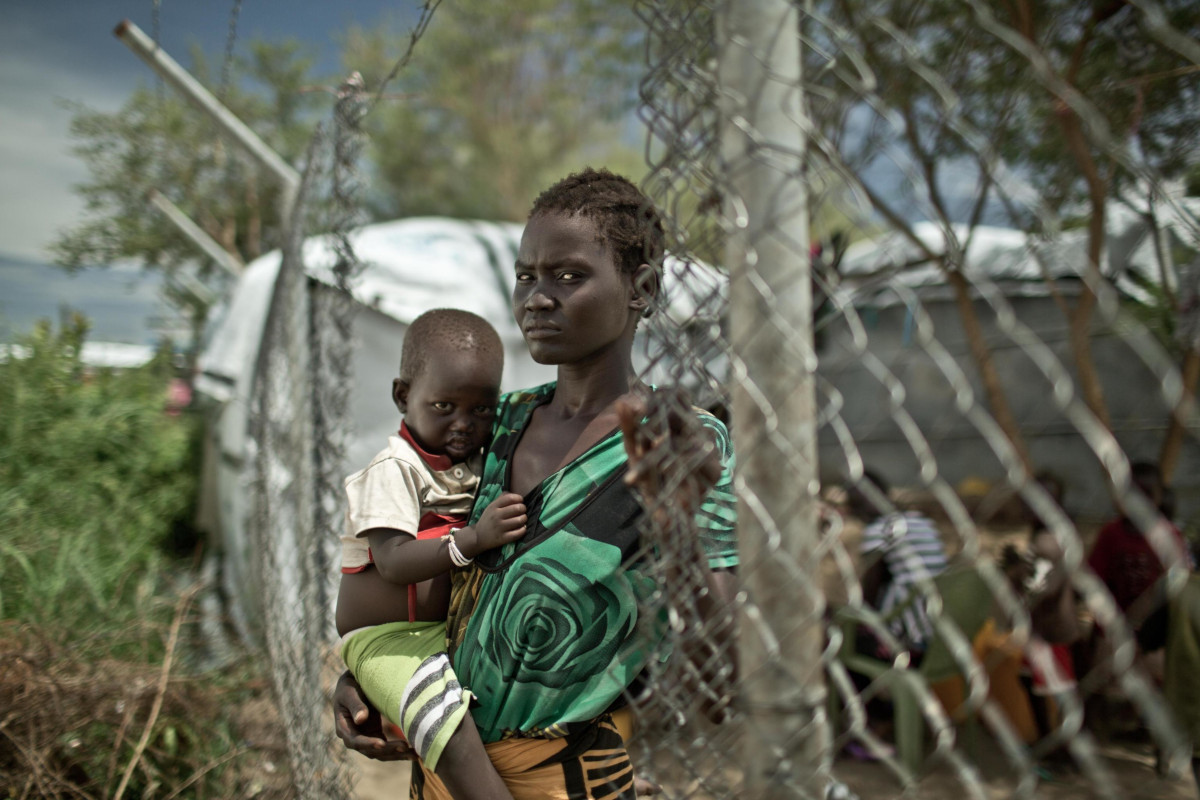 Una donna con un figlio in braccio in un campo per sfollati interni prevalentemente di etnia dinka a Mingkaman, Sud Sudan, 2014