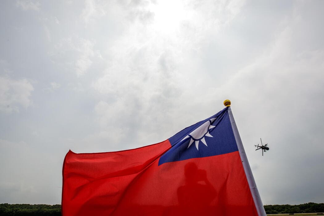 Dietro la bandiera nazionale, un elicottero Apache partecipa alle esercitazioni anti-invasione delle forze di Taiwan presso la base militare della provincia di Hsinchu, 21 settembre 2023