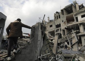 Un palestinese cammina tra i palazzi distrutti da un raid israeliano nel sud della Striscia di Gaza