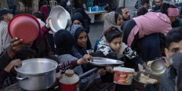 Palestinesi a Rafah fanno la coda per prendere del cibo donato da una Ong