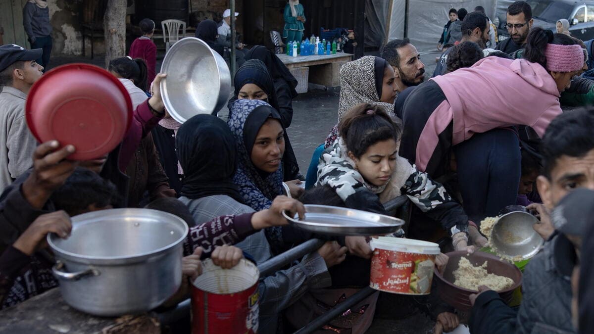 Palestinesi a Rafah fanno la coda per prendere del cibo donato da una Ong