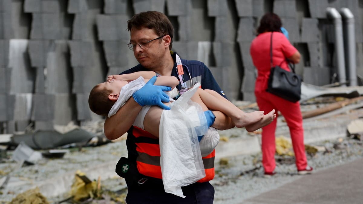 Un medico porta in salvo un bambino dopo che un missile russo ha colpito l'ospedale pediatrico Okhmatdyt di Kiev