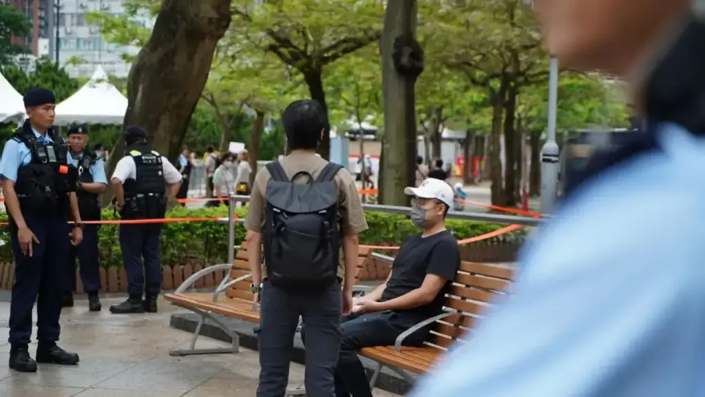 Un uomo seduto con una candela su una panchina vicino al Victoria Park a Hong Kong è stato portato via dalla polizia