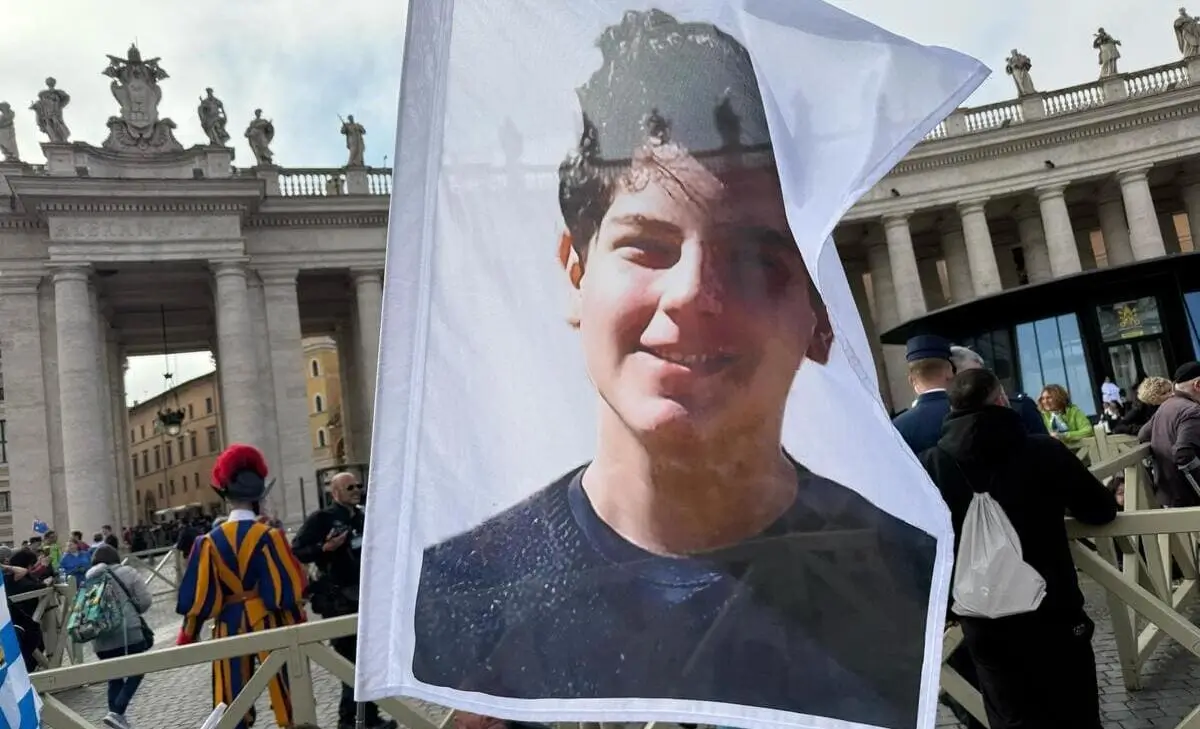 Un gruppo di ragazzi provenienti sventola bandiere con il volto di Carlo Acutis, piazza San Pietro, Città del Vaticano, 26 aprile 2025 (Foto Ansa)