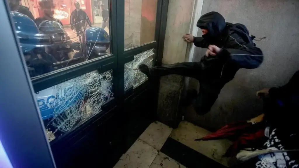 Un ragazzo rompe un vetro di una porta durante la manifestazione per Gaza a Milano