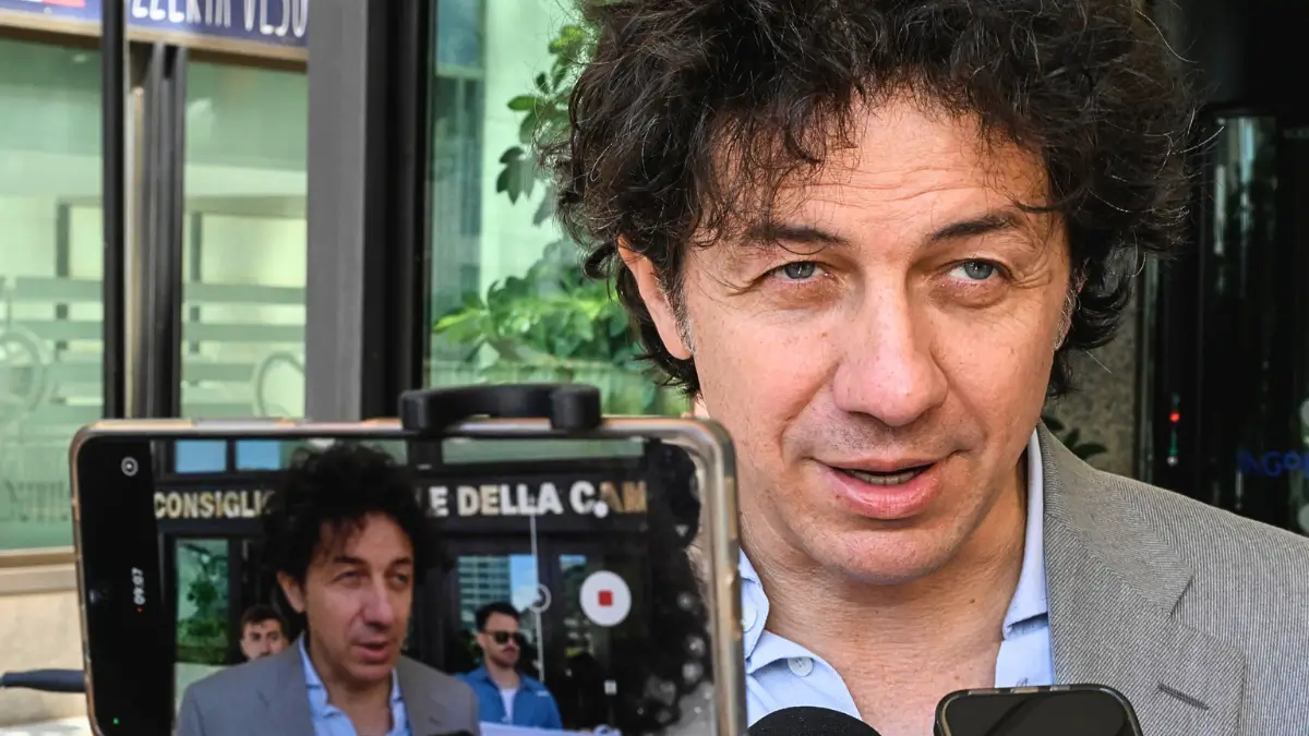 Marco Cappato, tesoriere dell'Associazione Luca Coscioni, è ripreso in un primo piano durante il presidio del 21 maggio a Napoli. L'iniziativa aveva lo scopo di sollecitare la discussione in Regione della proposta di legge “Liberi Subito” e l'accesso al suicidio assistito. La foto, scattata dall'Ansa, mostra Cappato con un'espressione decisa mentre parla, con uno smartphone che lo riprende in primo piano a sinistra