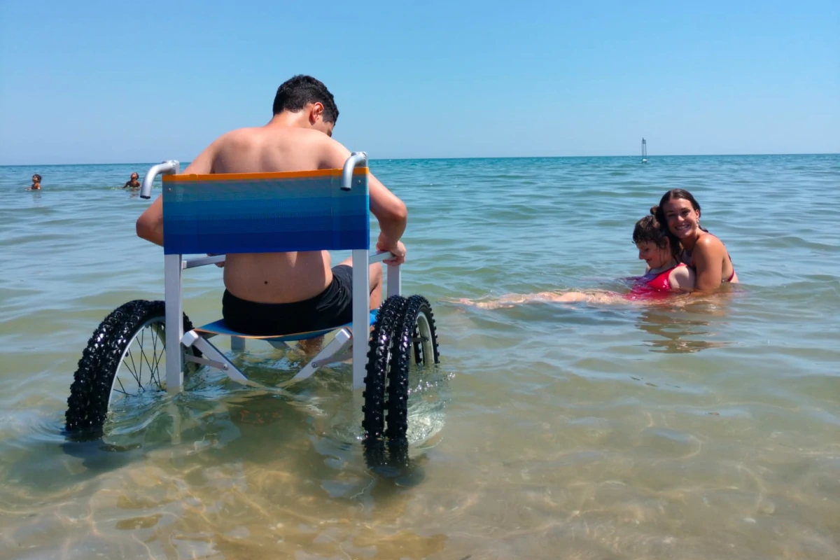 Ospiti e volontari di “Spiaggia libera tutti” durante un bagno nel mare di Rimini (foto Amici di Gigi)