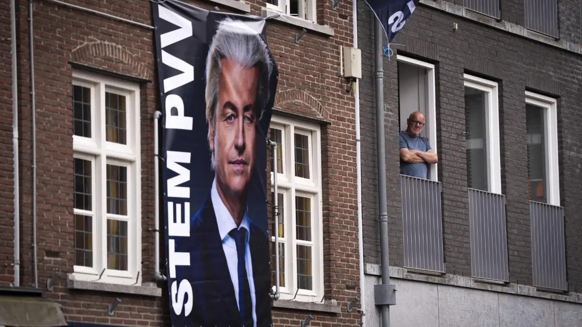 Una bandiera elettorale verticale con il ritratto di Geert Wilders del PVV (Partito per la Libertà) è appesa sulla facciata di un palazzo di mattoni. Il ritratto è grande e in primo piano, con la scritta 