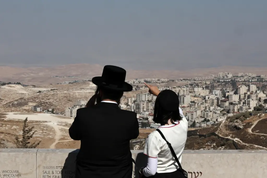 Una coppia di israeliani osserva da Gerusalemme il maxi insediamento di Ma’ale Adumin in Cisgiordania, 20 agosto 2025 (foto Ansa)