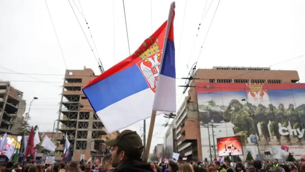 Un uomo sventola una bandiera serba sul sito dell'ex edificio dello Stato maggiore generale per celebrare il 26° anniversario della campagna di bombardamenti della Nato del 1999 a Belgrado, in Serbia