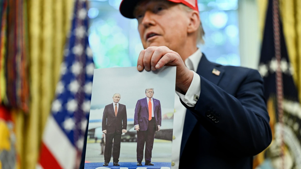 Il presidente americano nello Studio ovale della Casa Bianca mostra una foto che lo ritrae insieme al suo omologo russo Vladimir Putin, 22 agosto 2025 (foto Ansa)