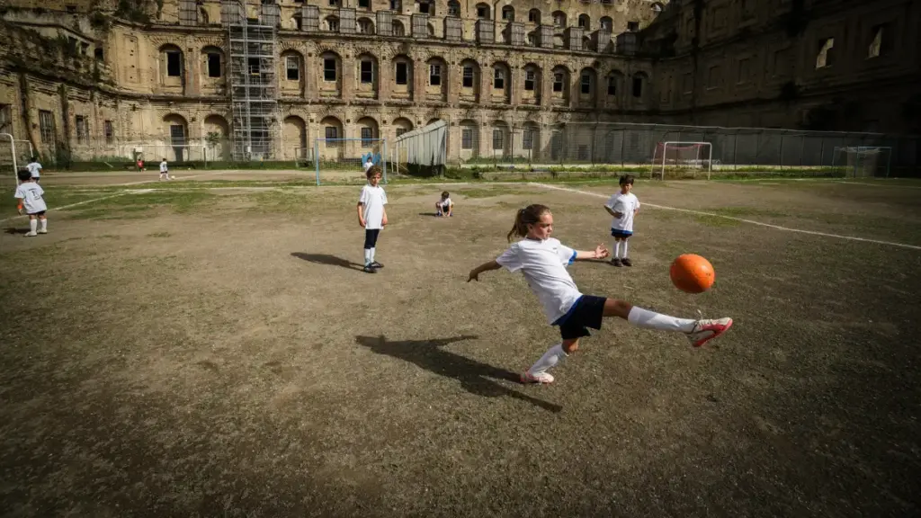 Una bambina palleggia con un pallone da calcio insieme ad altri bambini durante un momento della manifestazione “Alleniamoci per la pace” presso la scuola calcio dell’albergo dei poveri di Napoli, 20 maggio 2024 (foto Ansa)