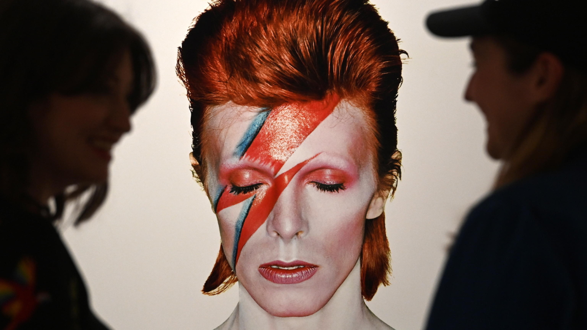 Due persone osservano l’iconica copertina dell’album “Aladdin Sane” di David Bowie, in mostra a Londra per i 50 anni dalla sua uscita, nell’aprile 2023