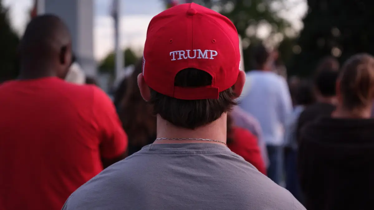 Un ragazzo, fotografato di spalle, indossa un cappellino rosso MAGA con la scritta Trump