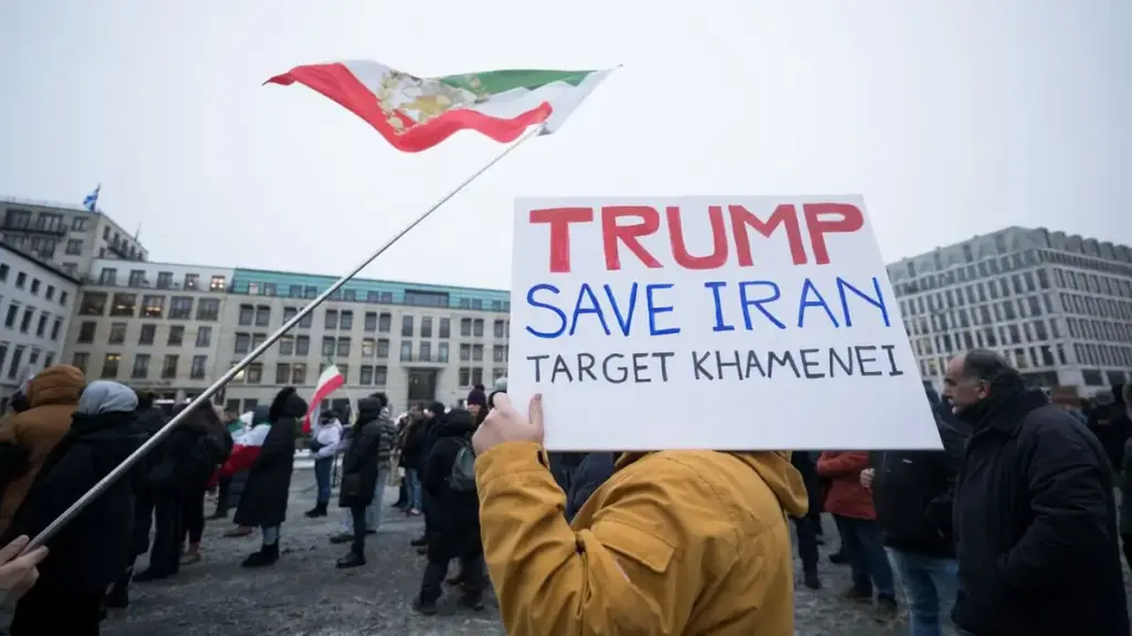 Manifestazione a Berlino a sostegno del popolo iraniano: un uomo mostra un cartello e chiede a Trump di salvare l'Iran e colpire Khamenei