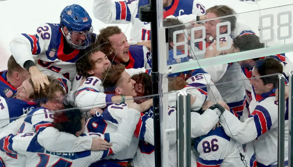 I giocatori della Nazionale degli Stati Uniti di hockey festeggiano la vittoria in finale contro il Canada alle Olimpiadi di Milano-Cortina. Sommerso dagli abbracci, con il numero 86, l’autore del gol-vittoria Jack Hughes (foto Ansa)