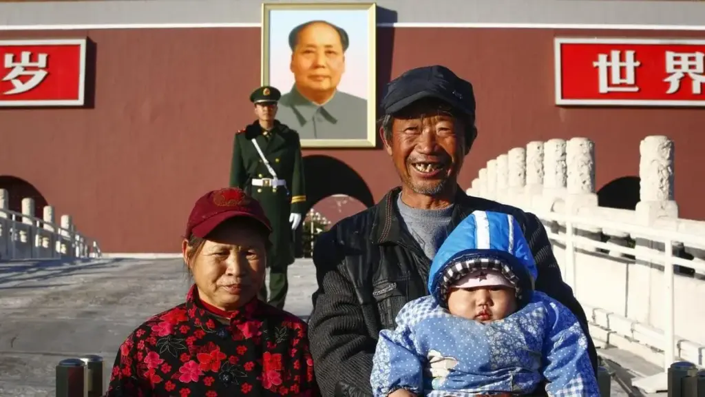 Una famiglia cinese con un solo figlio si fa scattare una foto davanti al ritratto di Mao in Piazza Tiananmen a Pechino