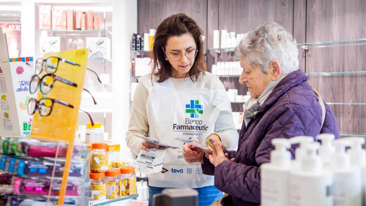 Una cliente di farmacia dona farmaci a un volontario delle Giornate di raccolta del farmaco