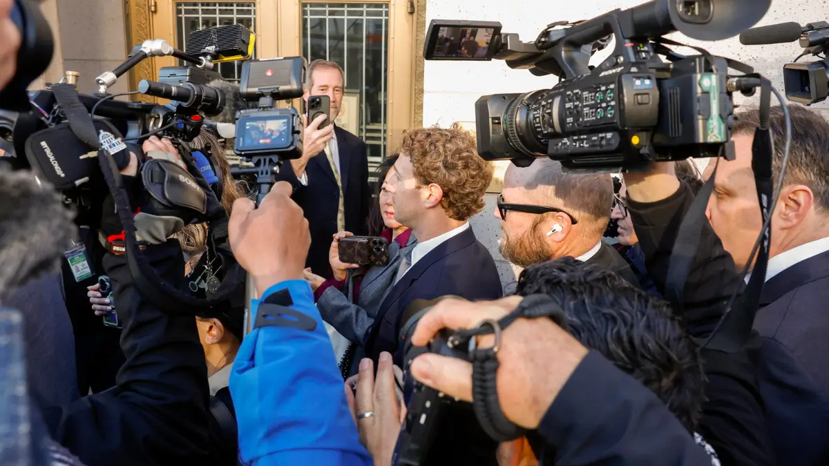 Mark Zuckerberg circondato dai giornalisti prima dell’udienza presso la Corte Superiore della Contea di Los Angeles, 18 febbraio 2026. Il ceo di Meta deve rispondere all’accusa per la quale le sue piattaforme creano dipendenza fra i giovani, danneggiando la loro salute mentale