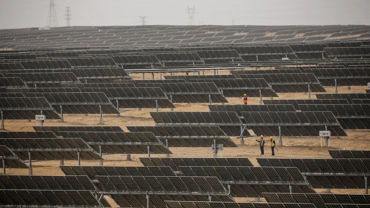 Alcuni tecnici ispezionano un campo di pannelli fotovoltaici a Ordos, in Cina