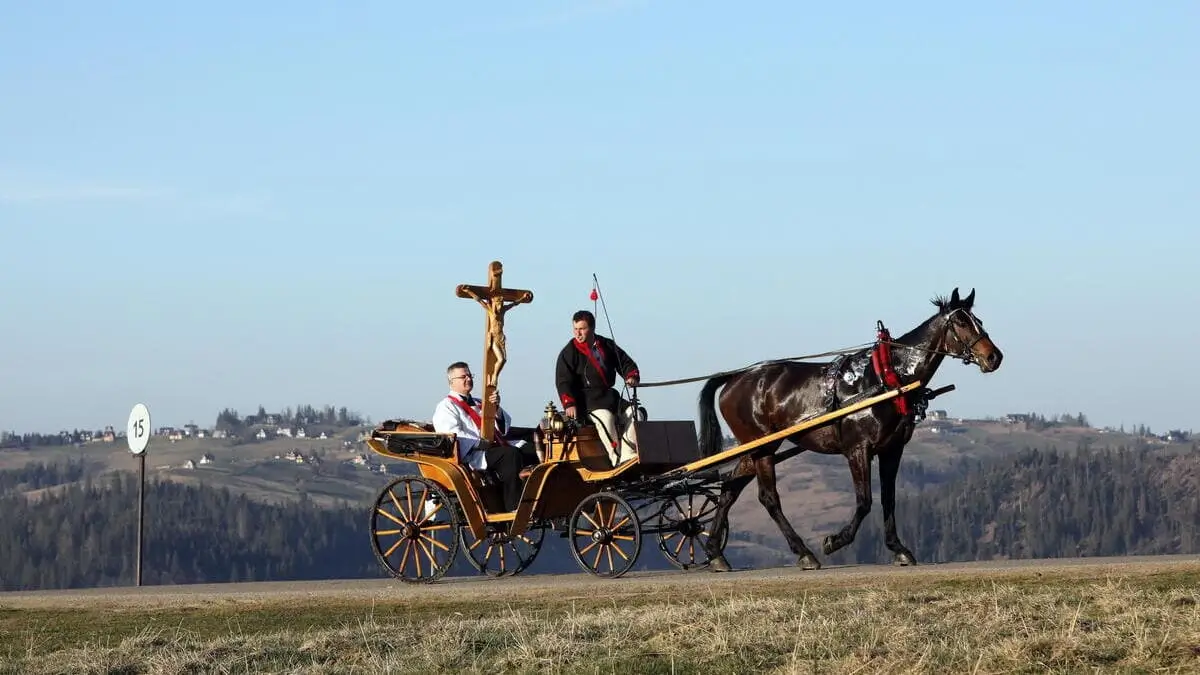 Un sacerdote cattolico regge una croce mentre viaggia su una carrozza trainata da cavalli per le strade di Zakopane, sui Monti Tatra, nella Polonia meridionale, il 10 aprile 2020, durante le celebrazioni pasquali del Venerdì Santo, nel contesto della pandemia di coronavirus.