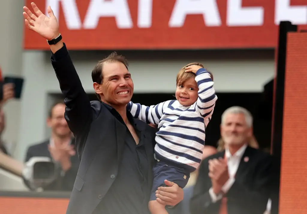 Il tennista spagnolo Rafael Nadal sul campo centrale del Roland Garros saluta i tifosi dopo il suo ritiro dal tennis. In braccio tiene il figlio Rafael Jr.