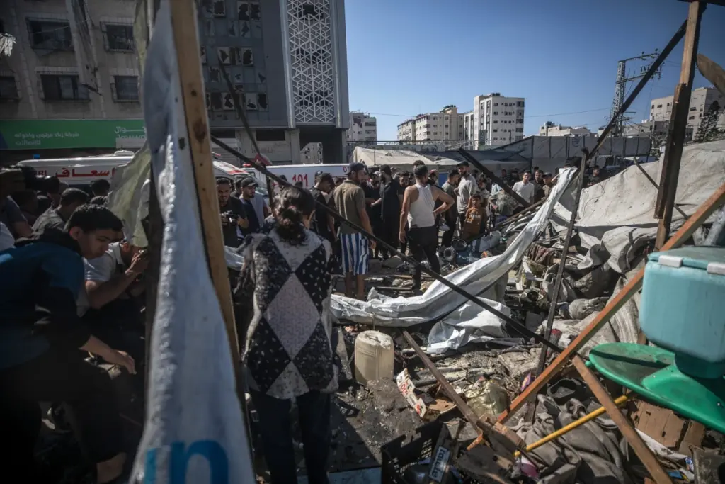 Palestinesi tra quel che resta del loro accampamento distrutto da bombardamenti israeliani a Gaza City, 27 giugno 2026 (foto Ansa)