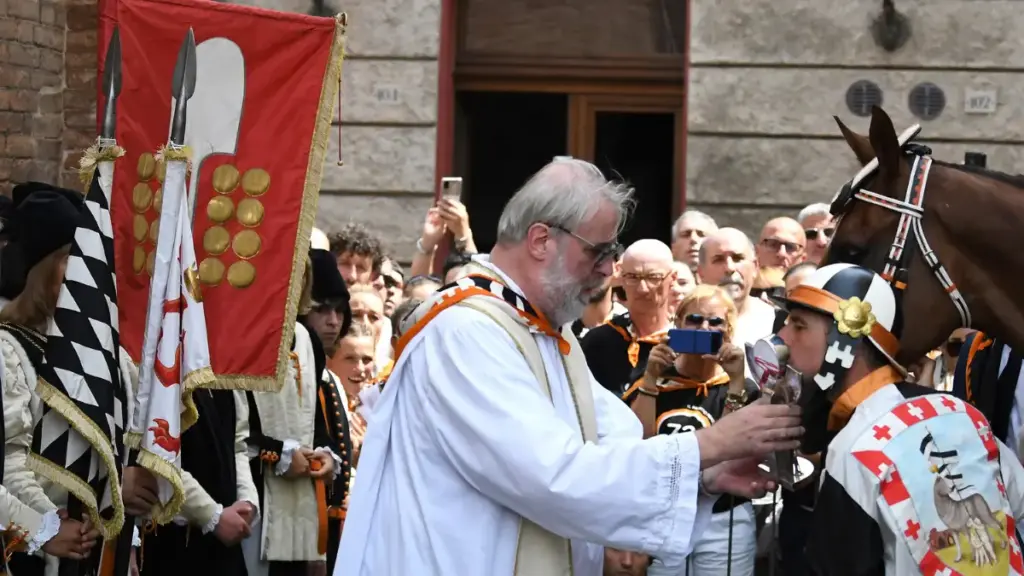 Don Massimiliano Gabbricci durante i riti della benedizione del cavallo prima del Palio di Siena
