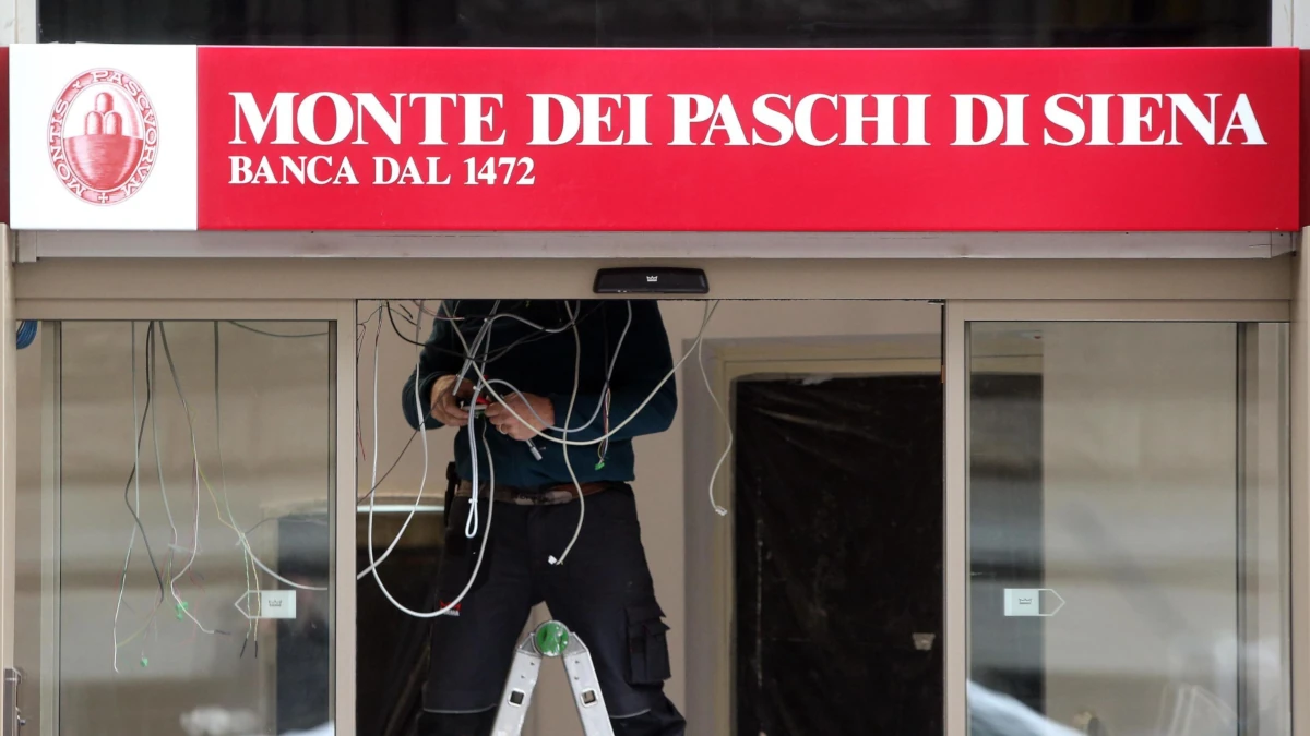 Tecnico al lavoro su una insegna &ldquo;Monte dei Paschi di Siena&rdquo; all&rsquo;ingresso di una filiale Mps (foto Ansa)