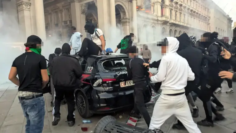 Un gruppo di ragazzi assalta un'auto dei carabinieri in piazza Duomo a Milano durante gli scontri di sabato 17 ottobre nel capoluogo lombardo