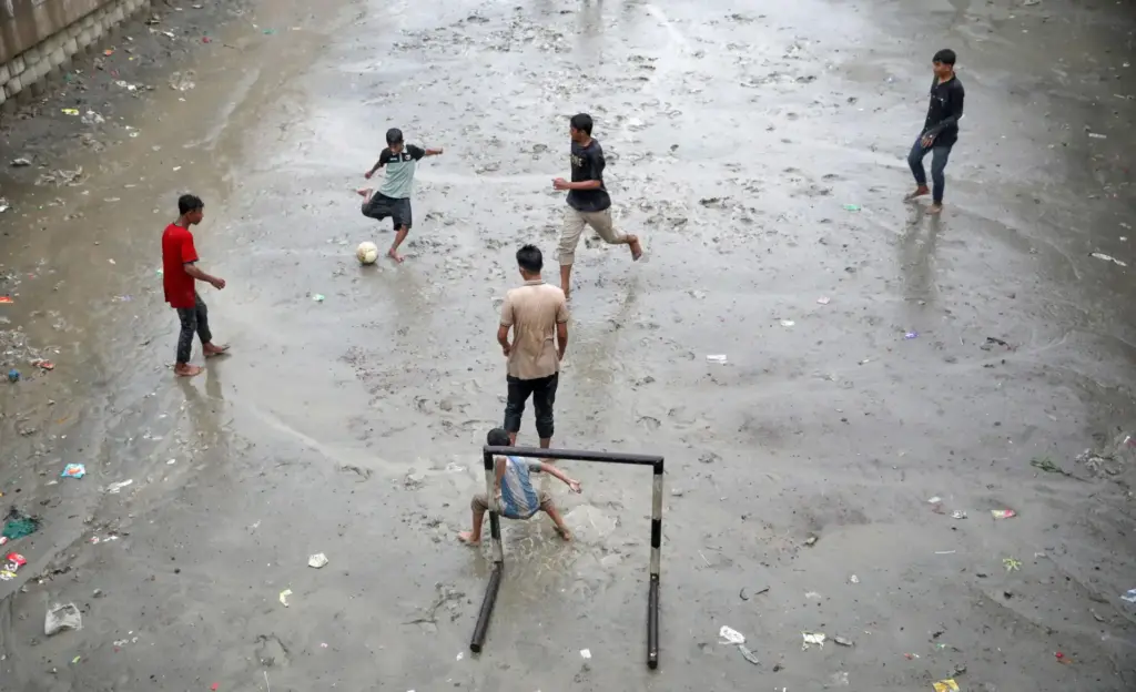 Bambini giocano a calcio sotto la pioggia a Dhaka, in Bangladesh, il 25 maggio 2026